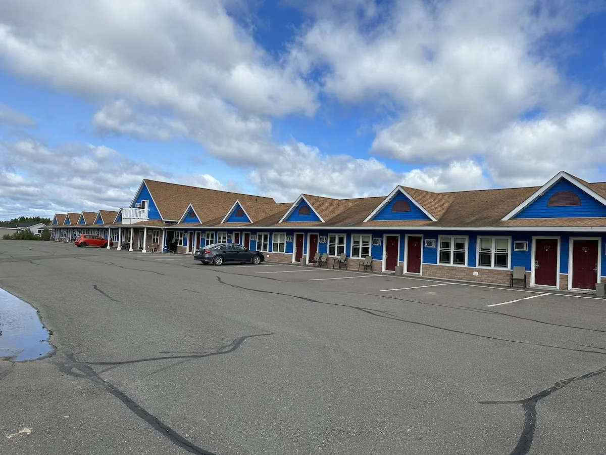 Travellers Inn seen across its parking lot, with blue gables and a wide sky